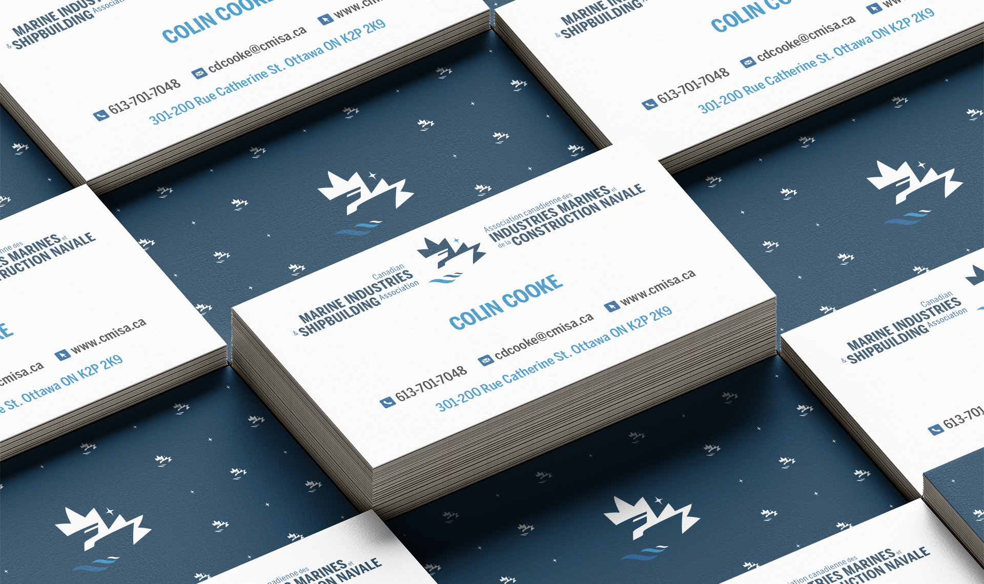 Stacked CMISA business cards: white front with blue text and centred logo; navy back with white logo mark and pattern.