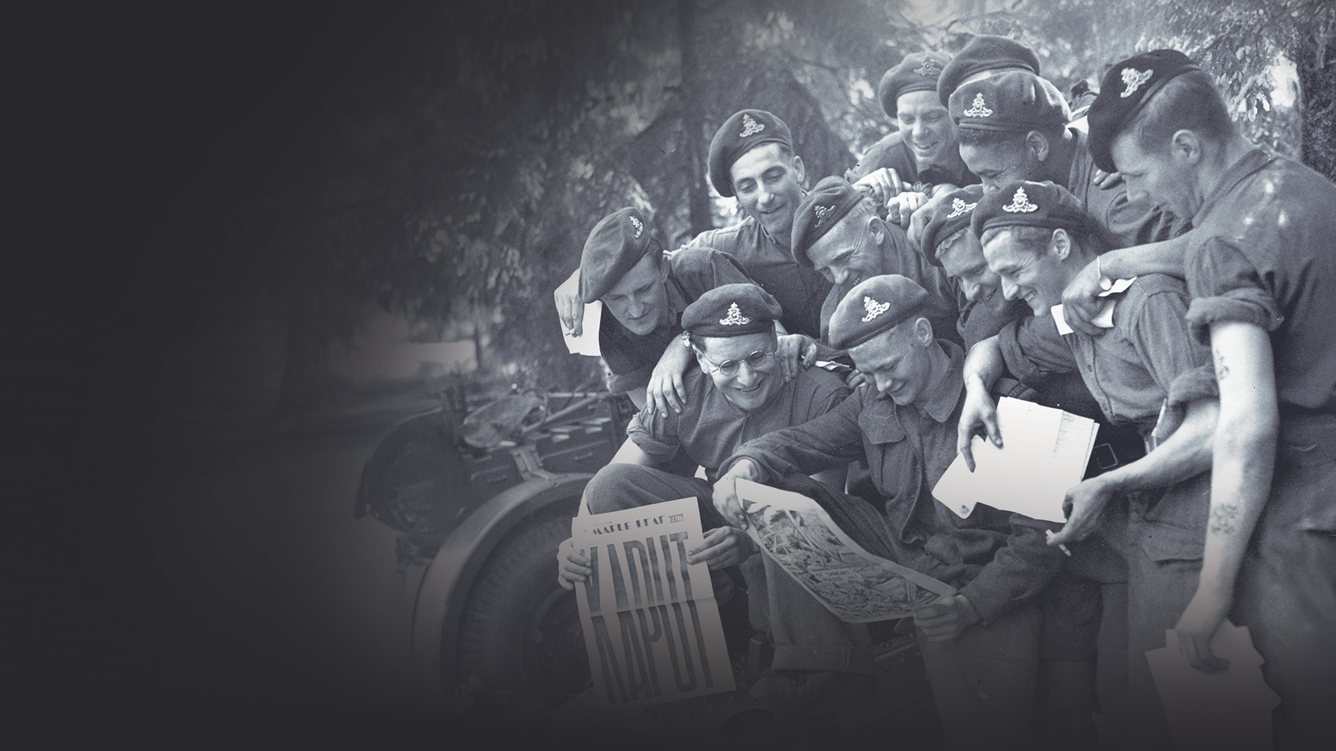 Photograph of Gunners with the 12th Field Regiment, Royal Canadian Artillery, looking at a newspaper with KAPUT on the cover.